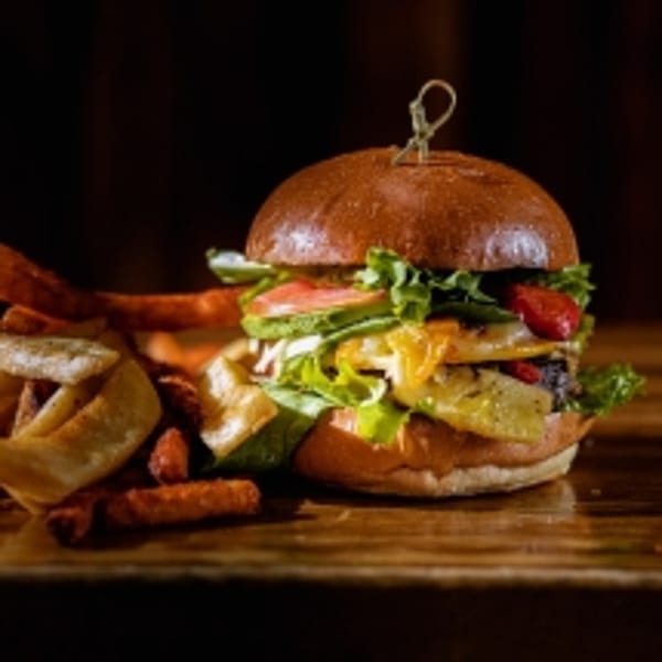 A BB's Burger Factory burger with pineapple, cheese, and vegetables, served with fries.